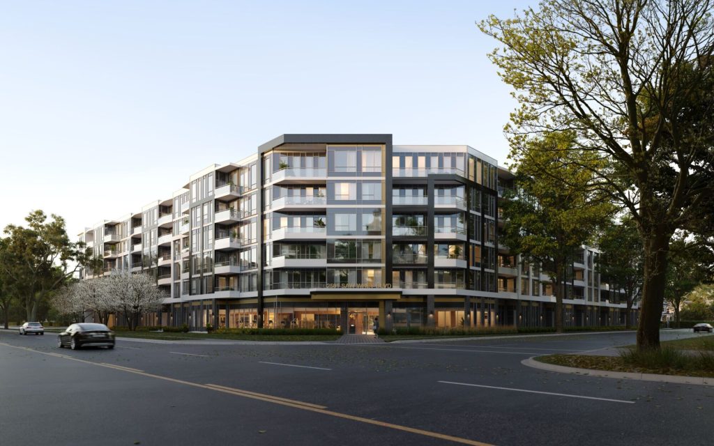 The curved corner of a mid-rise condominium building seen from across an intersection, its balconies and ground-floor retail lit at dusk.